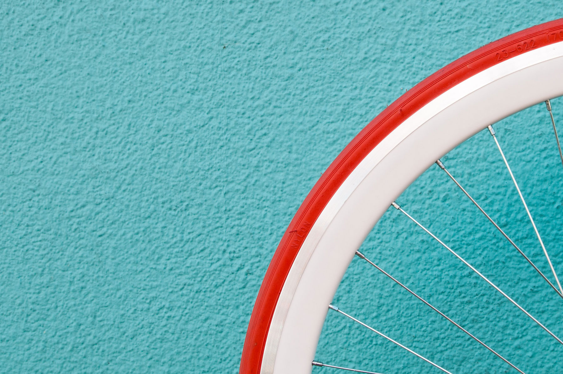 Roue de vélo rouge et blanche sur fond turquoise