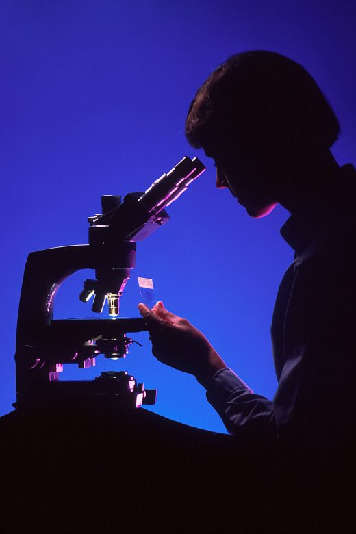 Homme dans l'ombre face à un microscope