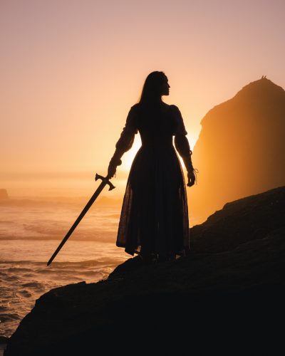 Photo en contrejour d'une femme avec une épée au bord de l'eau